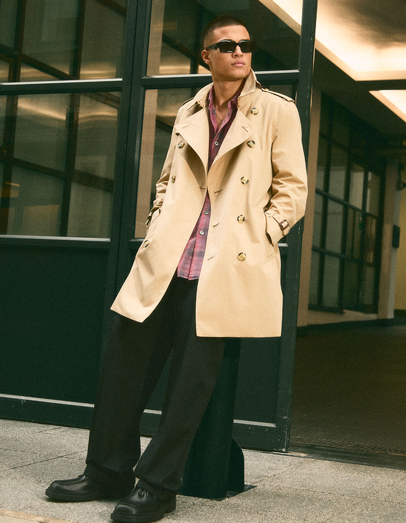 Model wears a preppy trench coat outfit with pieces by Miu Miu, Gucci and Alexander McQueen